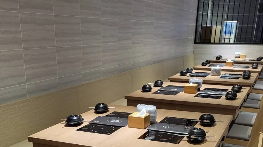 木質桌席沿牆排列並備妥個人鍋具的用餐空間