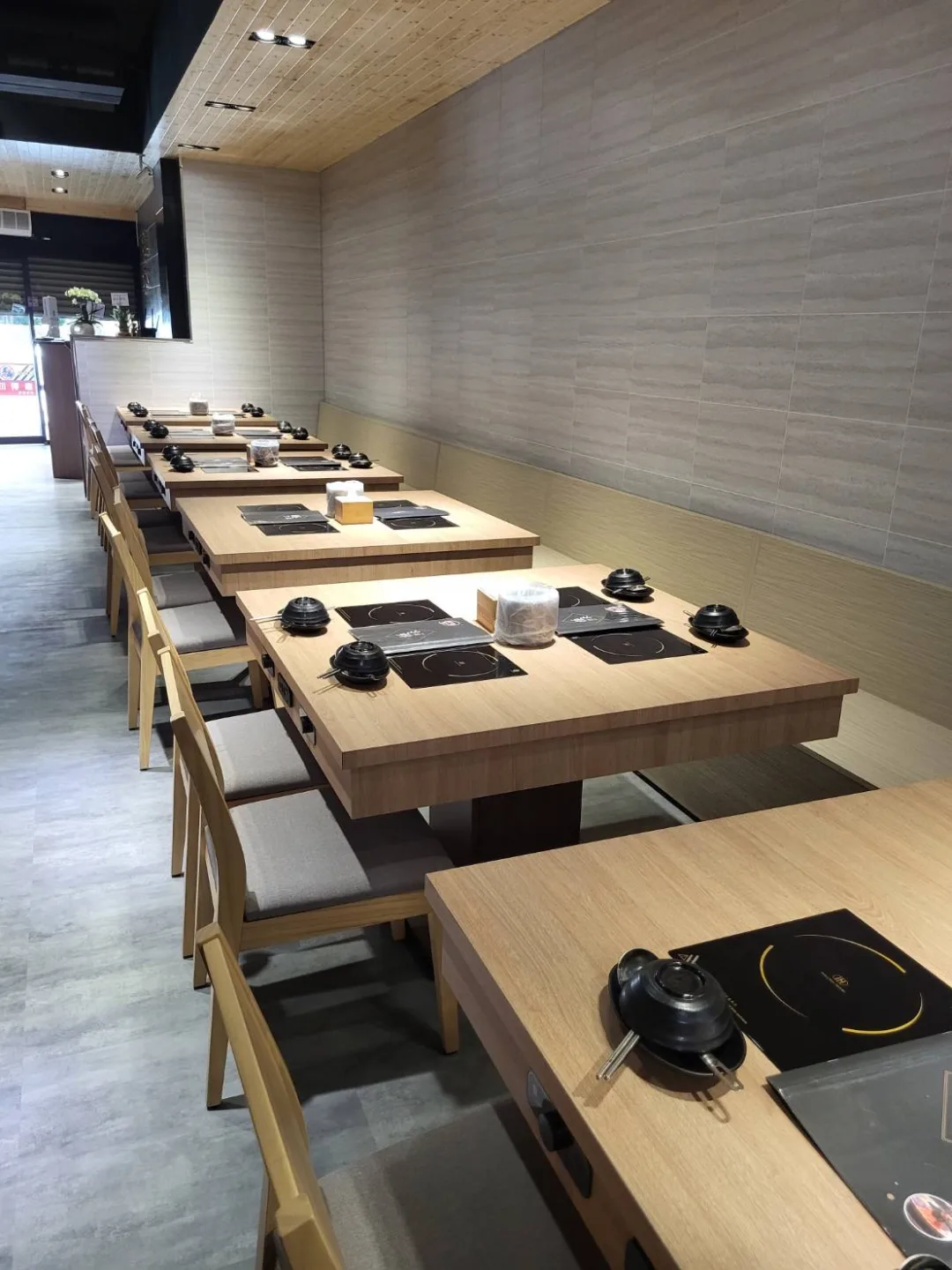 沿著淺木牆面延伸排列的火鍋餐桌與座位