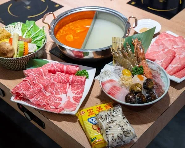 雙味湯鍋旁擺放肉盤、海鮮與蔬菜