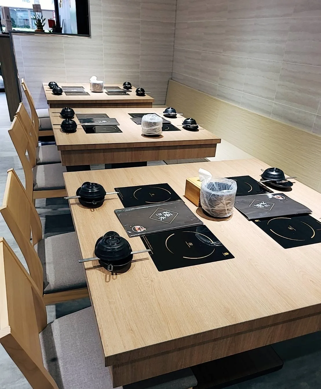 三張木質餐桌依序備妥個人鍋具與餐具的桌席近景